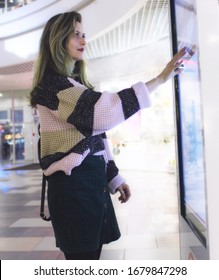 Woman touching interactive information kiosk at mall - using navigation system. Technology and informatization concept