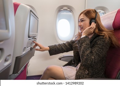 Woman Touching LCD Entertainment Screen On The Airplane In Flight Time.