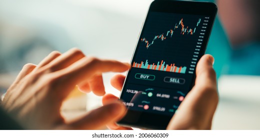 Woman touching mobile phone investing application. Stock market investment app in hand. Screen close-up - Shutterstock ID 2006060309