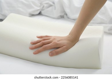 Woman touching orthopedic memory foam pillow on bed, closeup. Space for text - Shutterstock ID 2256085141