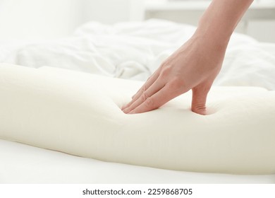Woman touching orthopedic memory foam pillow on bed, closeup. Space for text - Shutterstock ID 2259868705