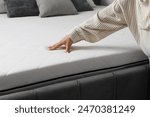 Woman touching soft orthopedic mattress on bed at home, closeup