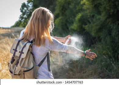 Woman tourist applying mosquito repellent on hand during hike in nature. Insect repellent. Skin protection against tick and other insect. 
