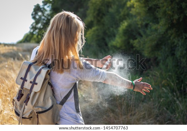 Woman tourist applying mosquito repellent on hand during\
hike in nature. Insect repellent. Skin protection against tick and\
other insect. 