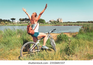 Woman tourist in bicycle enjoying Suscinio castle view in Morbihan, Brittany, France
