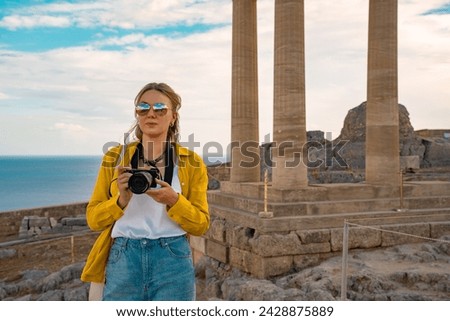A woman tourist with a camera in the Acropolis on an excursion.