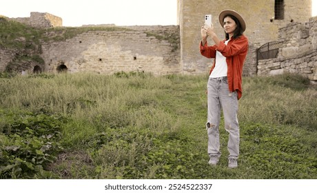 Woman tourist capturing photos of an ancient fortress for a travel blog. She enjoys documenting historical landmarks and sharing her travel experiences online, exploring culture and architecture. - Powered by Shutterstock