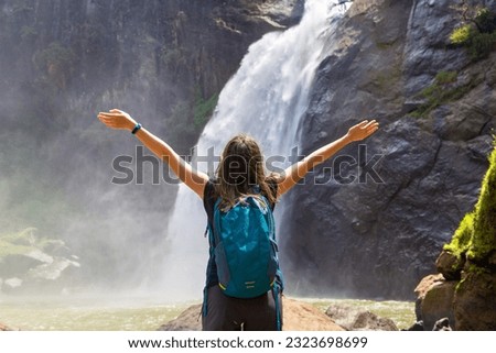 Woman tourist and Dunhinda waterfall in a sunny day in Sri Lanka
