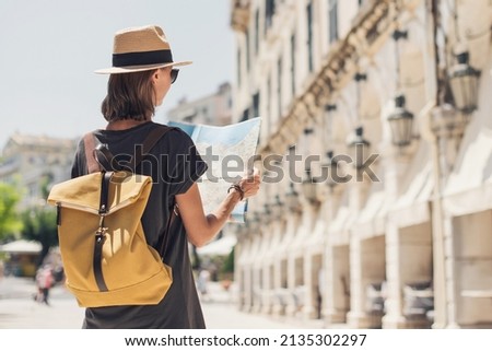 Woman tourist enjoying vacation in old town, looking at travel map. Travel alone, active lifestyle, enjoy life, summer fun, holidays, vacations, people concept