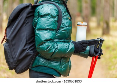 Woman tourist in the forest with backpack and trekking sticks
