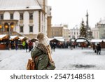 Woman tourist is going to Christmas market at town square during Advent holiday. Lifestyle in city at winter