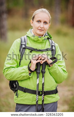 woman tourist with hiking equipment walking in forest