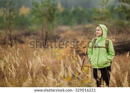woman tourist with hiking equipment walking in forest