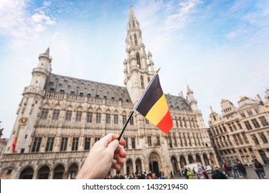 Woman tourist holds in her hand a flag of Belgium against the background of the Grand-Place Square in Brussels, Belgium. Traveling in Belgium, the main attraction of Brussels, the Grand Market Square
