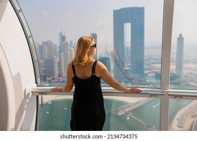 Woman tourist inside Ferris wheel cabin of Dubai Eye (Ain)  - One of the largest in the World, located on Bluewaters island. Top tourists attractions in the United Arab Emirates