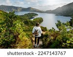 Woman tourist on hiking trail admiring scenic view of Lagoa do Fogo (Lake of Fire) - a crater lake on Sao Miguel Island, Azores, Portugal. Mountain hiking and wanderlust concept