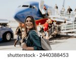 Woman tourist passager getting in to airplane at airport, walking from the terminal to the plane.