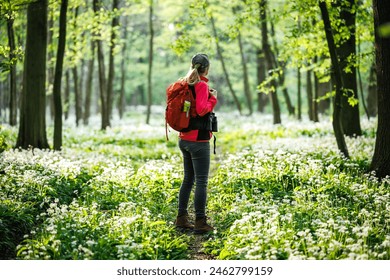 Woman tourist with red backpack hiking in spring forest. Hike and joy in nature. Female hiker explore woodland - Powered by Shutterstock