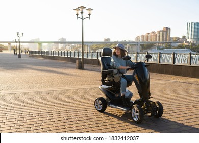 Woman tourist riding a four wheel mobility electric scooter on a city street.