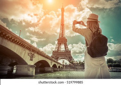 Woman tourist selfie near the Eiffel tower in Paris under sunlight and blue sky. Famous popular touristic place in the world. - Shutterstock ID 519799885