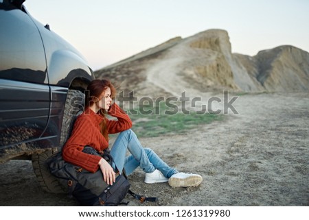 Woman tourist sitting leaning on the car in nature                