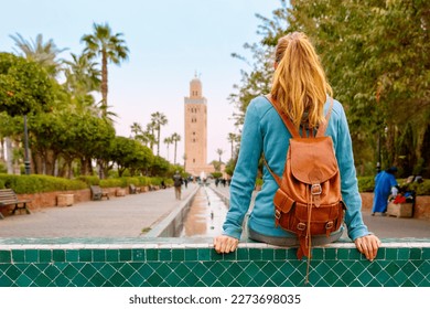 Woman tourist sitting and looking at Koutoubia mosque in Marrakesh, Morocco