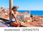 Woman tourist sitting on balcony looking at panoramic view of rooftop of Lisbon- Portugal