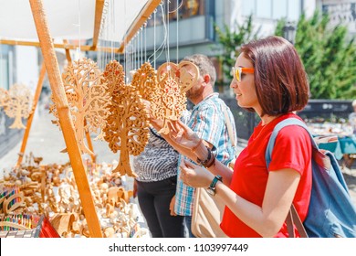 A woman tourist at a souvenir fair choosing handmade decorative woodcarving gifts