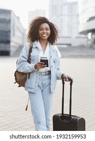 Woman Tourist With Suitcase Luggage Holding Passport And Tickets. Smiling Mixed Race Girl Portrait In A City. Business Travel, Student Lifestyle, People, Tourism Concept