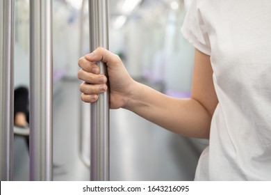 Woman tourist travel in the city by public city sky train system. Woman holding the hand rail in the train close up with copy space. Solo female tourist in modern lifestyle concept. Urban lifestyle.