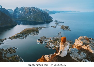 Woman tourist traveling in Norway active summer vacations adventure lifestyle outdoor in Lofoten islands, girl on cliff edge enjoying sea aerial view from Reinebringen mountain top - Powered by Shutterstock