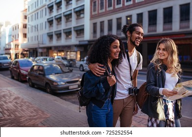 Woman Tourist Using Navigation Map To Explore The City. Man With Two Women Friends Moving Around The City.