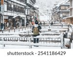 Woman tourist Visiting Ginzan Onsen in Yamagata, happy Traveler sightseeing Japanese Onsen village with Snow in winter season. landmark and popular for attraction in Japan. Travel and Vacation concept