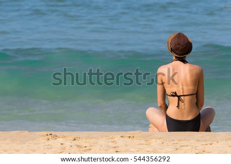 Woman Tourist Wearing Swimsuit and Hat is Sitting for Sunbathe and Relax on Nai Yang Sea Beach of Phuket, Thailand Set as Blank Frame for Text
