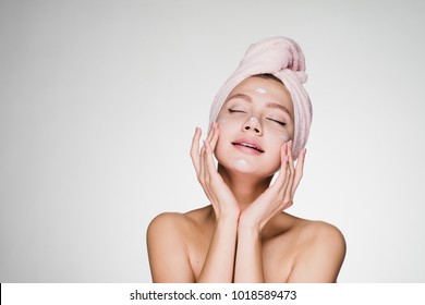 woman with a towel on her head puts cream on her face