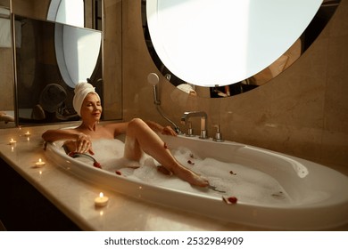 Woman with towel on her head, taking hot relaxing bath with salt and bubble bath. Beautiful young woman while enjoying bath. Lady on hotel vacation lying in bathtub. Girl while relaxing in float bath. - Powered by Shutterstock