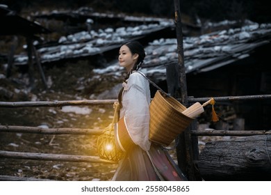 A woman in traditional attire carries a basket and a glowing lantern, walking beside a rustic wooden fence near an old building. - Powered by Shutterstock