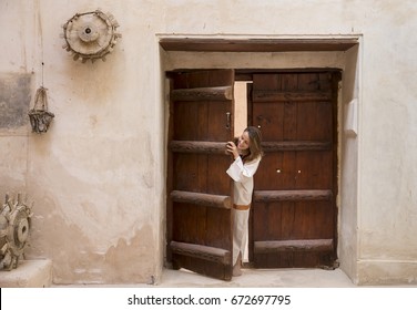 Woman In Traditional Clothing Looking Through And Old Doorway In An Old Castle In Oman