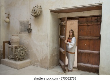 Woman In Traditional Clothing Looking Through And Old Doorway In An Old Castle In Oman