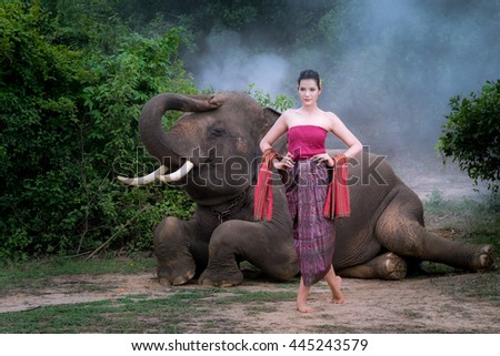 Woman with traditional thai dress hugs her elephant, at elephant village, Surin, Thailand