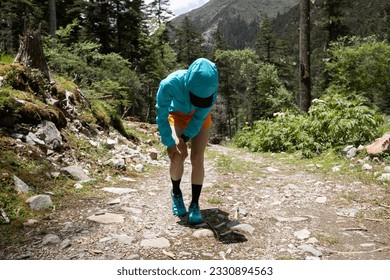 Woman trail runner got sports injury on her knee in high altitude mountains  - Shutterstock ID 2330894563