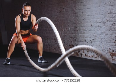 Woman training with battle rope in cross fit gym - Shutterstock ID 776152228