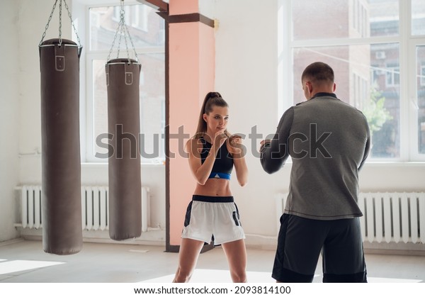 Woman training boxing\
with personal trainer. Instructor teaching female boxer fighting\
practice together