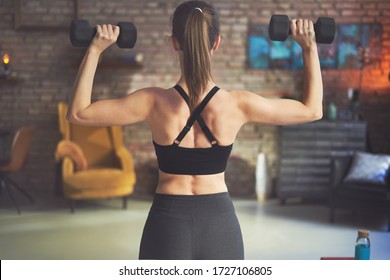Woman training, doing exercise and weight training at home in the living room. Concepts about home workout, fitness, sport and health.