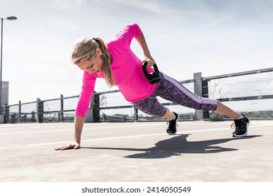 Woman training with dumbells- doing one-armed plank - Powered by Shutterstock