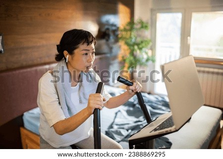 Woman training on smart stationary bike at home
