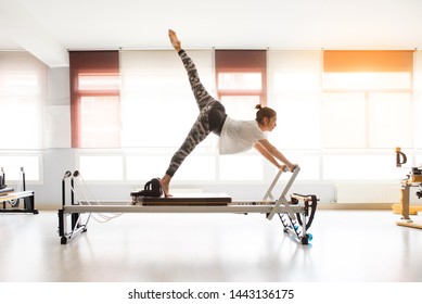 Woman training pilates exercises in covered gym