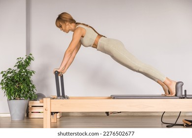 Woman training pilates on the reformer bed. Reformer pilates studio machine for fitness workouts in gym. Fit, healthy and strong authentical body. Fitness concept - Shutterstock ID 2276502677