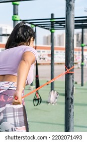 Woman Training Shoulders Using Elastic Rope Band Outdoors