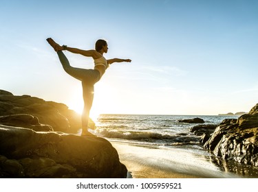 Woman Training Yoga On The Beach At Sunset